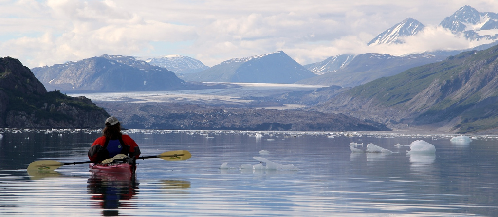 A Kayak guide paddles on a calm day towards the Grand Pacific Glacier